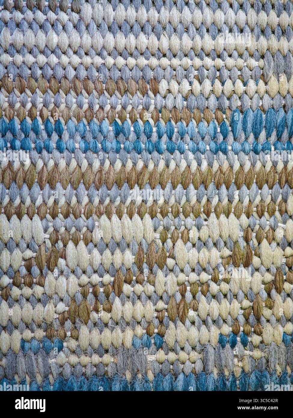 Nahaufnahme eines mehrfarbigen gewebten Teppichs in Blau-, Beige- und Brauntönen, mit detaillierter Textur und Muster. Stockfoto