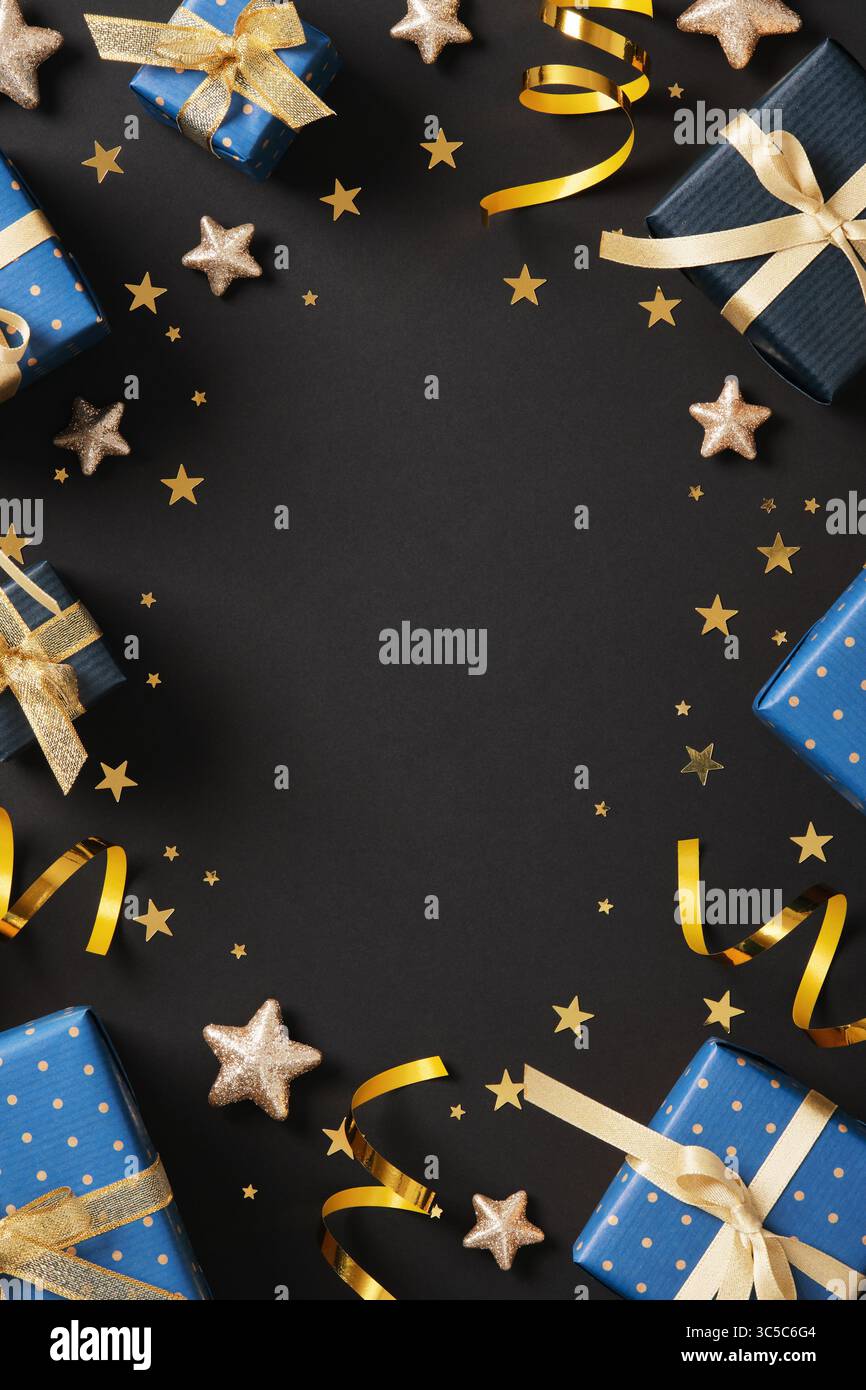 Vertikaler Rahmen aus Geschenkverpackungsmaterial. Blaues Geschenkpapier, goldene Bänder, Tags, Schere, Konfetti. Platz für Ihren Text. Stockfoto