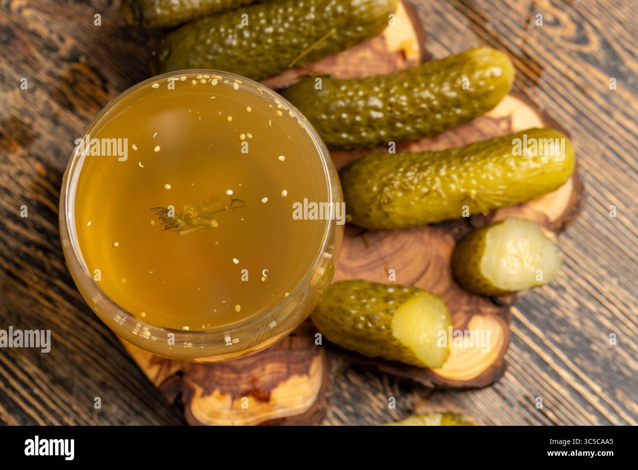 Eingelegte Gurken und eingelegte reife Gurken neben einem Glas, eingelegte Gurken mit Gewürzen und ganze knusprige Gurken auf ein Brett, Nahaufnahme Stockfoto