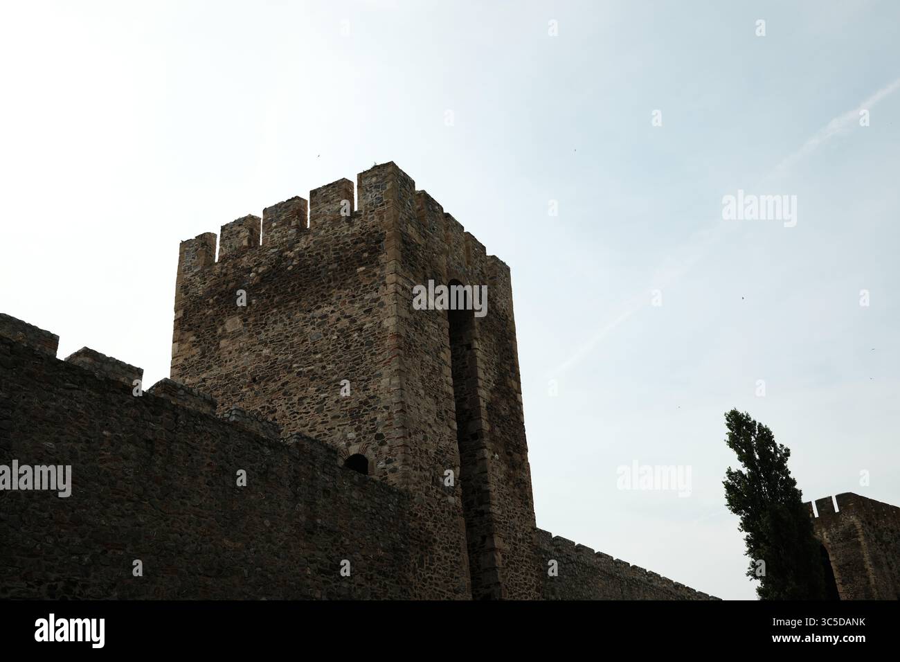 Nahaufnahme eines massiven Steinturms der Festung Smederevo, Serbien, mit Zinnen und einer hohen bogenförmigen Öffnung gegen den blassbewölkten Himmel. Stockfoto