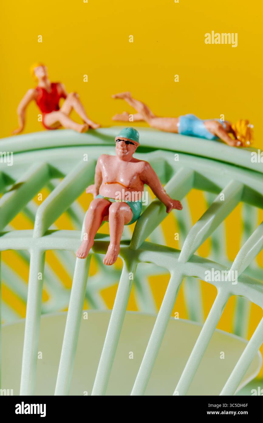 Drei kleine Strandgäste ruhen sich aus und sitzen auf der geschwungenen Oberfläche eines blassgrünen Ventilators und ahmen eine ungezwungene Pause am Pool unter einer imaginären Sonne nach Stockfoto