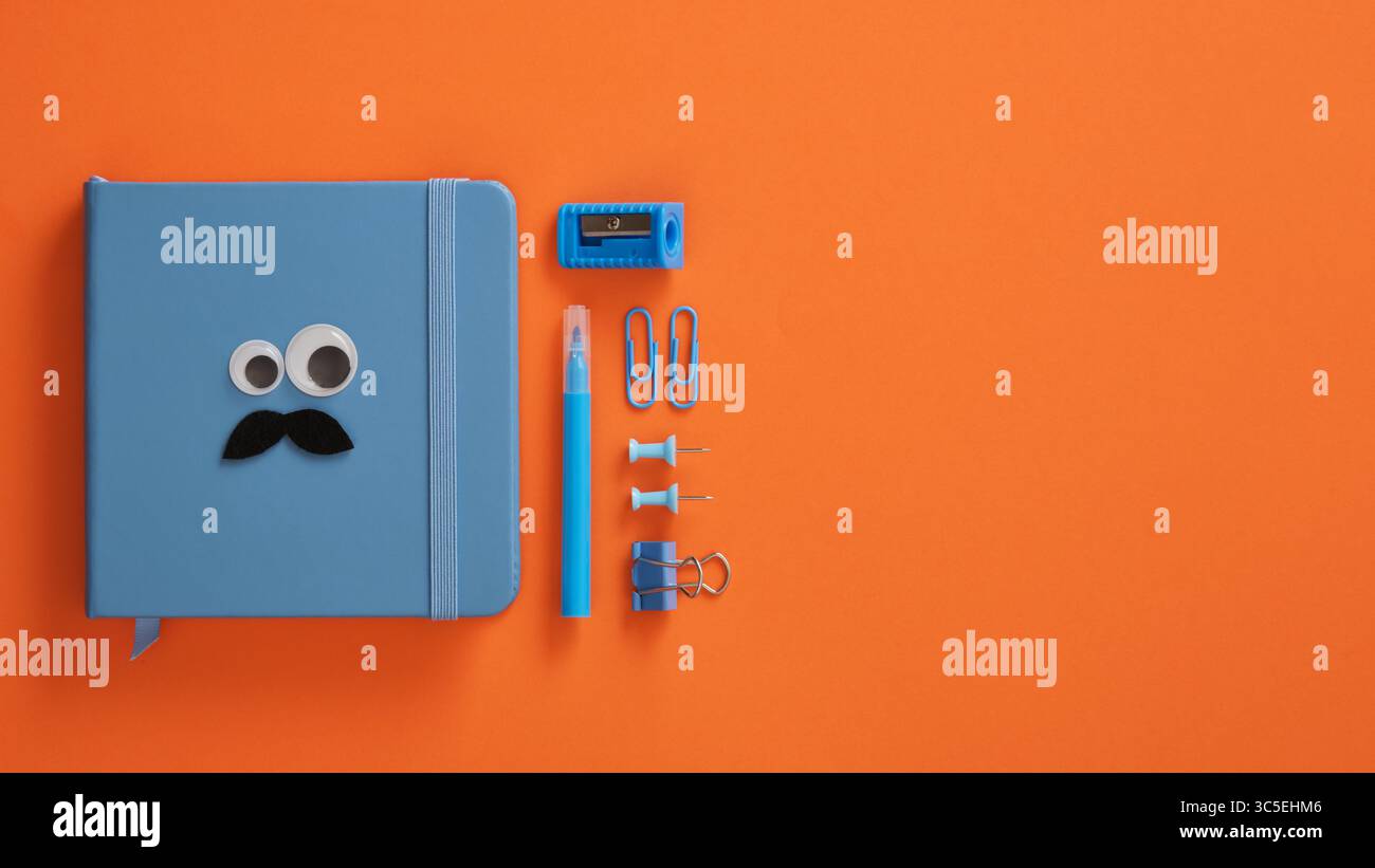 Blauer Notizblock mit Augen und Schnurrbart und Briefpapier auf einem leuchtend orangen Hintergrund. Platz für Ihren Text. Stockfoto