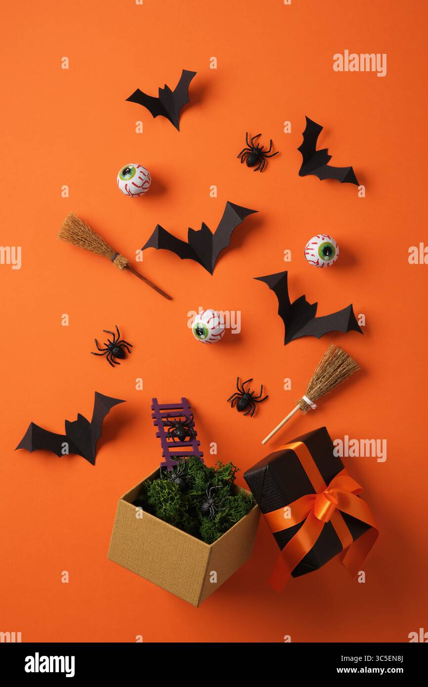 Halloween-Tag mit Fledermäusen, Besen, Besen, Augen, Spinnen auf orangem Hintergrund. Hintergrund für Banner, Poster, Grüße und Halloween-Feiern. Stockfoto