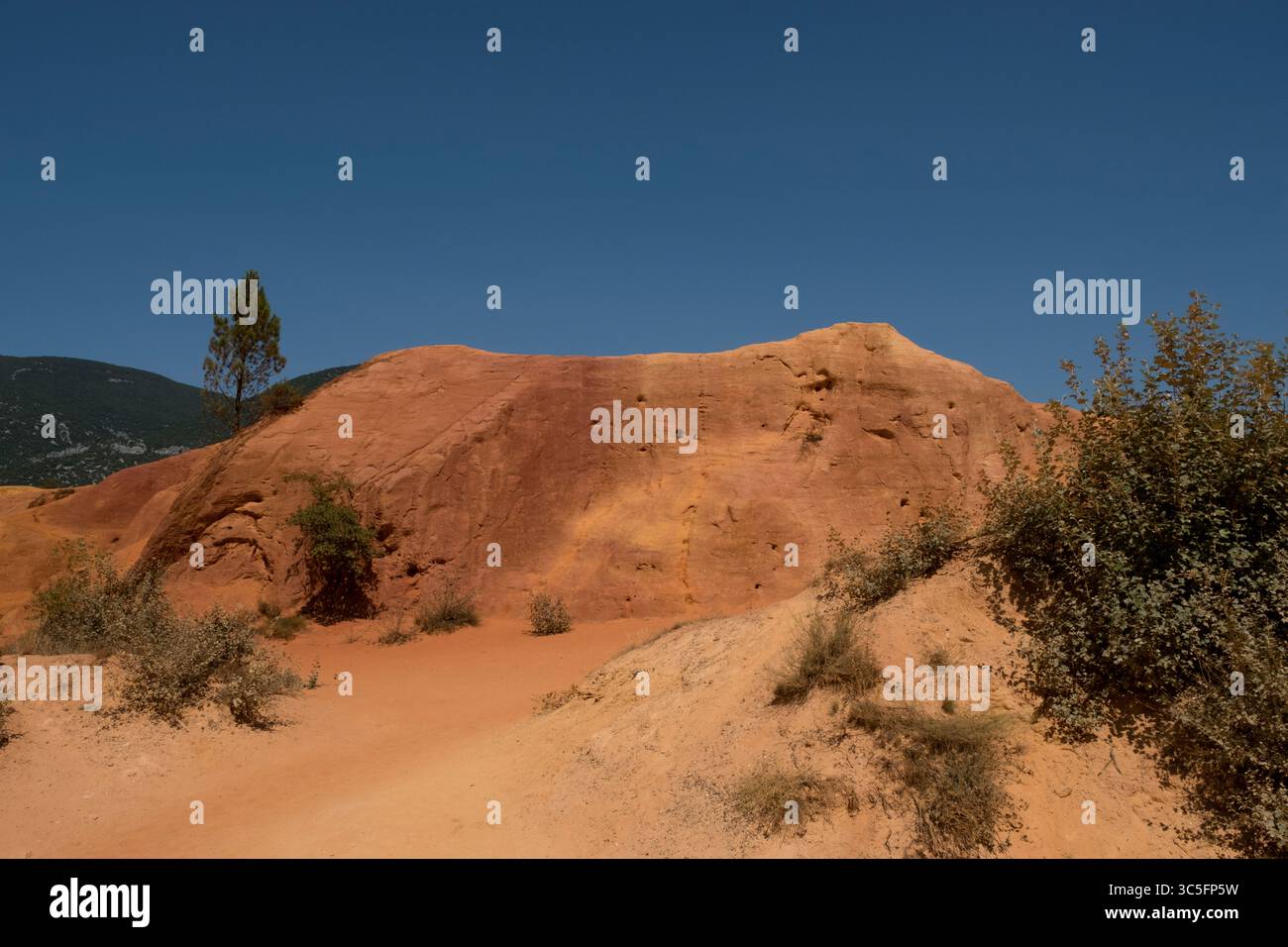 Markante rote Felsformationen in den Hügeln der Provence, Frankreich, unter einem klaren blauen Himmel. Eine farbenfrohe und einzigartige Landschaft, die durch die Zeit des natürlichen Elements geformt wurde Stockfoto