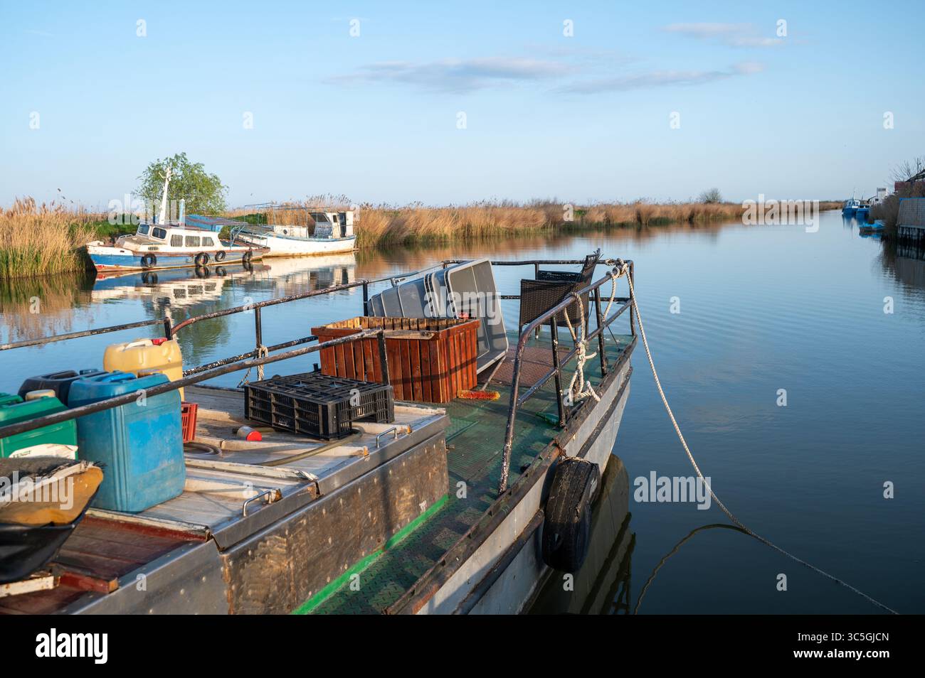 Fischerboot mit Kisten und Netzen, das in einem ruhigen Kanal angedockt ist Stockfoto