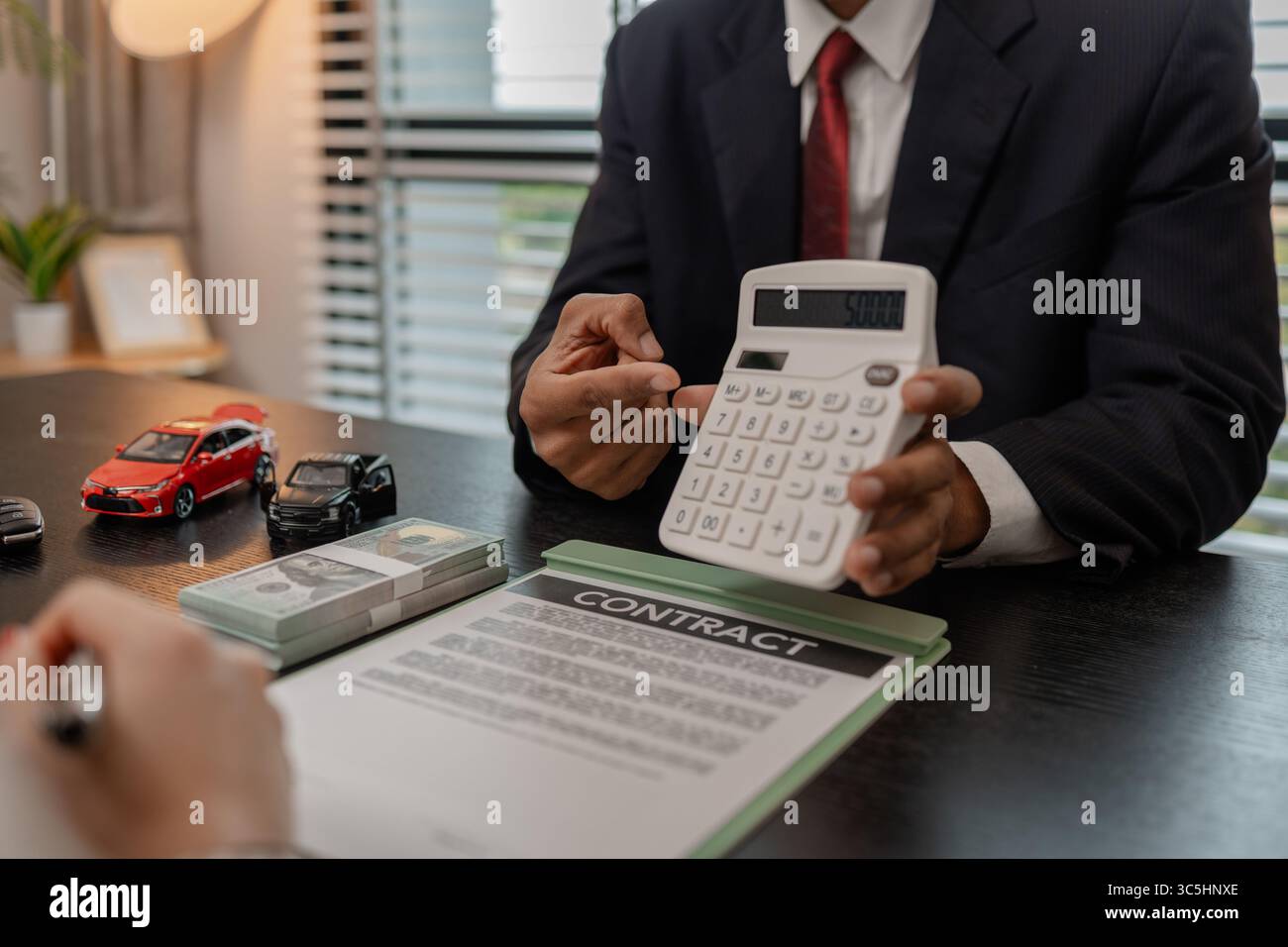 Ein Autoverkäufer erklärt die Details eines Autos und den Preis, an dem ein Käufer interessiert ist, der Verkaufsleiter des Verkaufsraums erläutert die Menge an Int. Stockfoto