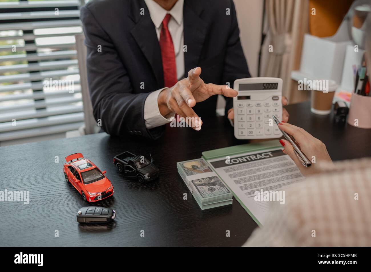 Ein Autoverkäufer erklärt die Details eines Autos und den Preis, an dem ein Käufer interessiert ist, der Verkaufsleiter des Verkaufsraums erläutert die Menge an Int. Stockfoto