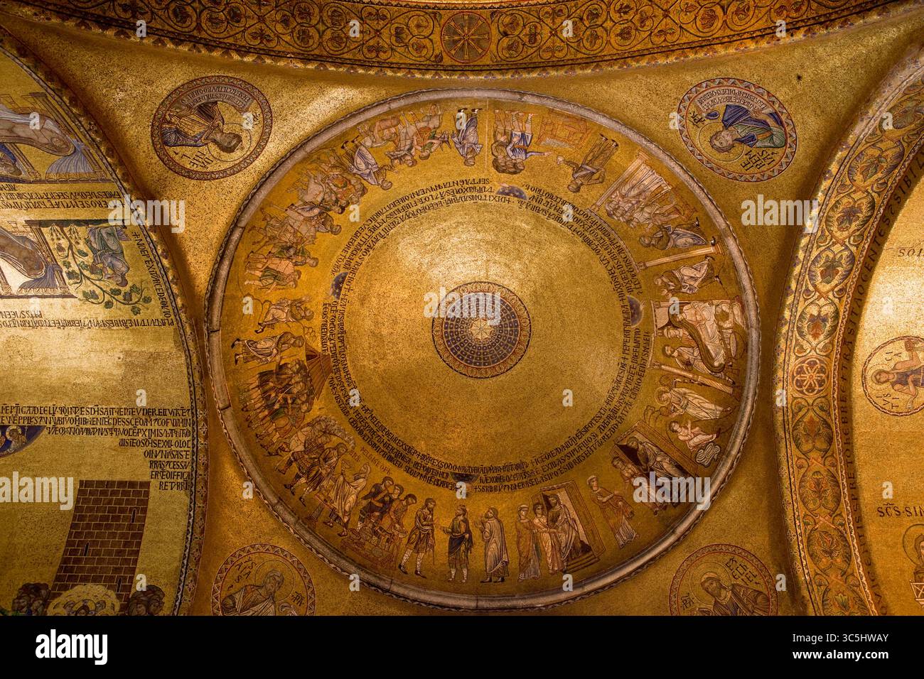 Blick auf die goldene Mosaikkuppel im Inneren des Markusdoms in Venedig. Das byzantinische Design zeigt konzentrische biblische Szenen, lateinische Inschriften, A Stockfoto