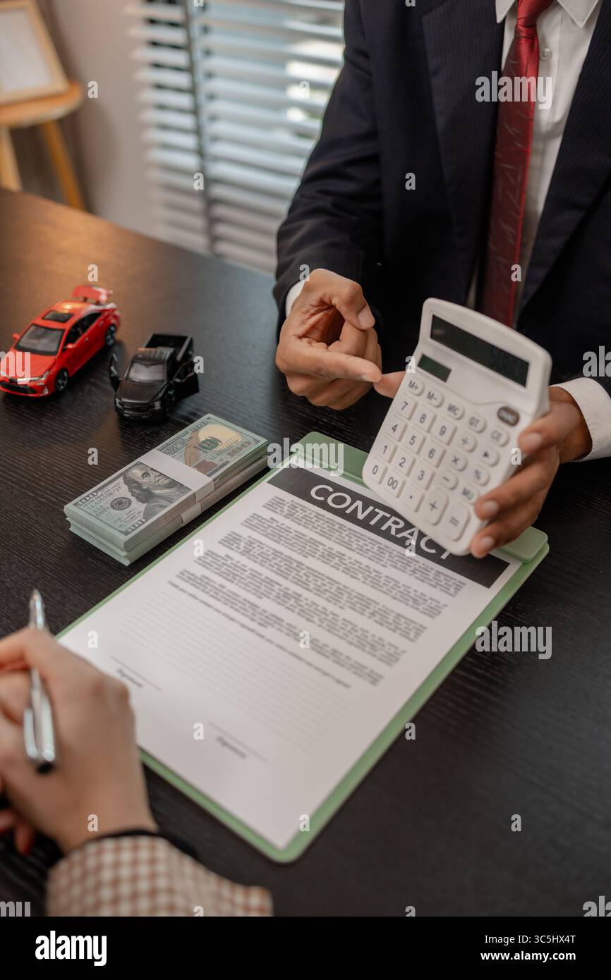 Ein Autoverkäufer erklärt die Details eines Autos und den Preis, an dem ein Käufer interessiert ist, der Verkaufsleiter des Verkaufsraums erläutert die Menge an Int. Stockfoto
