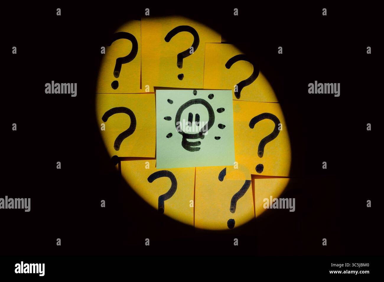 Beleuchteter Scheinwerfer, umgeben von Fragezeichen, die auf farbigem Papier mit schwarzem Marker mit einheitlichem, solidem Hintergrund gezeichnet sind Stockfoto