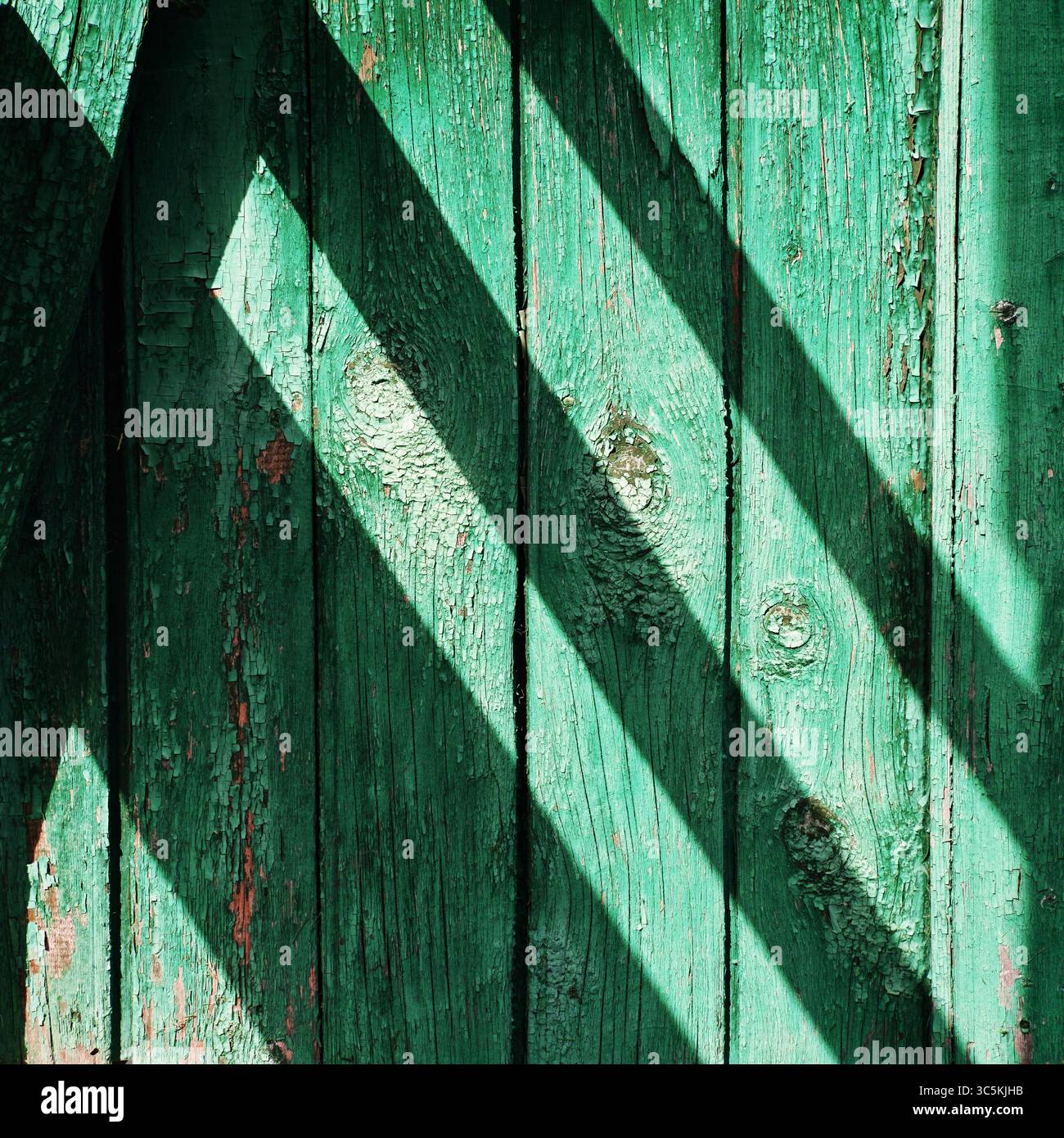 Detail der grünen Holzwand mit vertikalen Dielen und markanten diagonalen Schatten Stockfoto