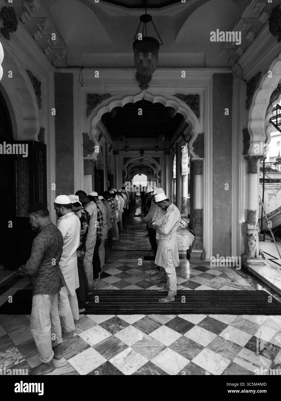 Sie stehen still im Gebet im Korridor von Juma Masjid, Mumbai, und suchen Frieden, während die Welt weiter geht. Ein ruhiger Moment inmitten der Hektik der Stadt Stockfoto