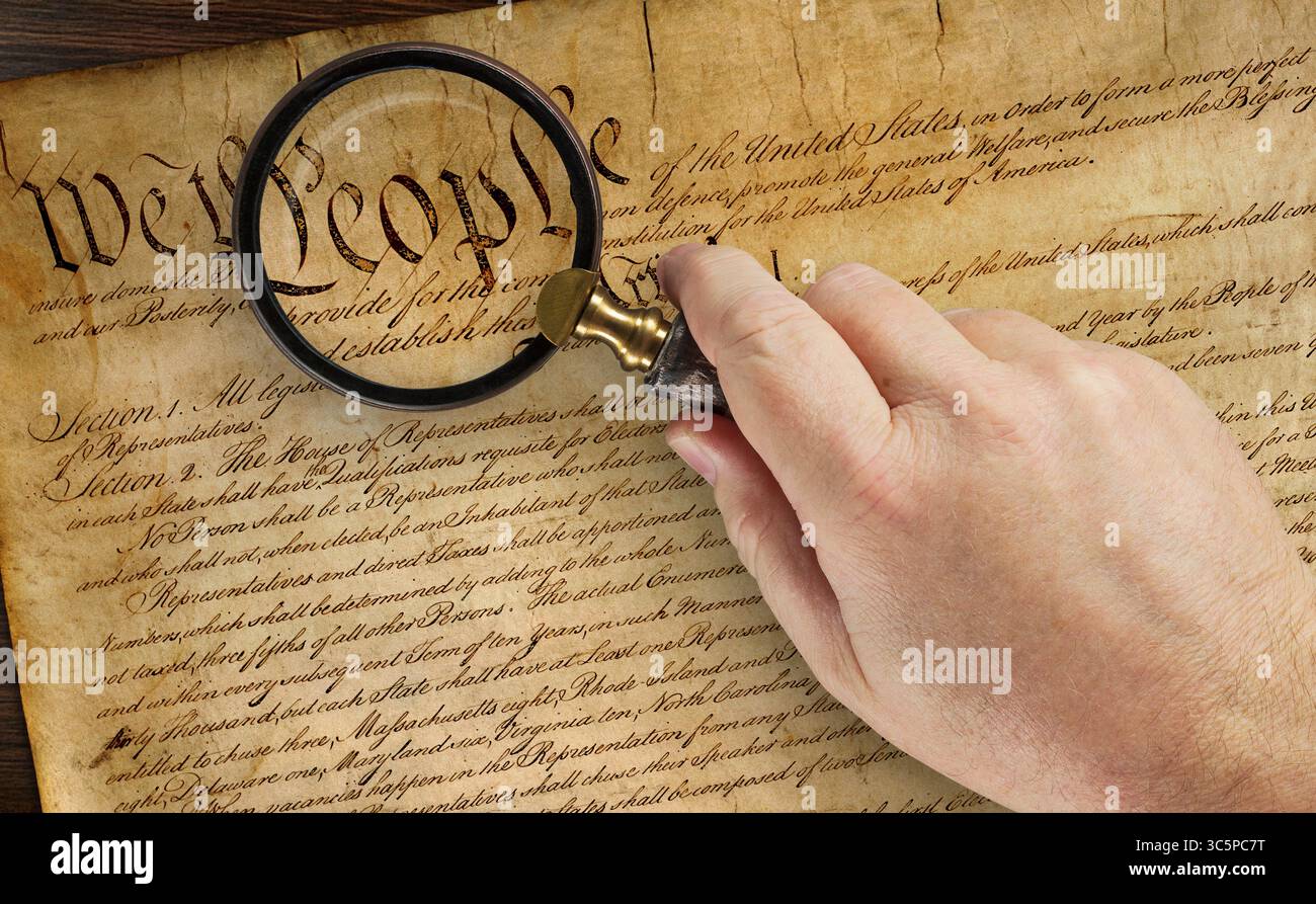 Männliche Hand, die Vergrößerungsglas über die Arbeitsleute der Verfassung der Vereinigten Staaten hält. Stockfoto