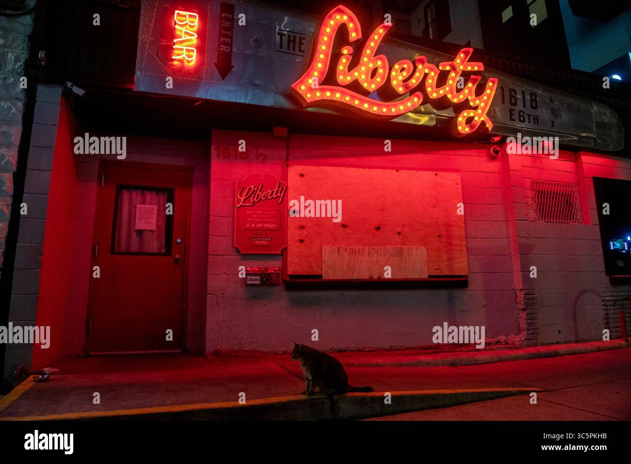 19. März 2020: Eine Nachbarschaftsbar-Katze sitzt an einem Bordstein vor der Liberty Bar in der E 6th St Austin Texas, die ihre Fenster bis auf weiteres aufgrund von Einschränkungen der Coronavirus-Pandemie geschlossen und eingelassen hat. (Bild: © Sandy Carson/ZUMA Wire) Stockfoto