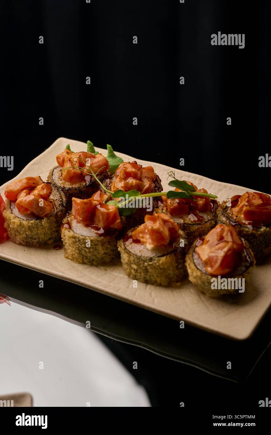 Sushi-Brötchen mit Lachs, Frischkäse und Sauce auf schwarzem Hintergrund Stockfoto