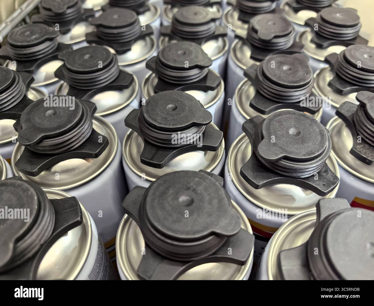 Reihen ordentlich organisierter Farbsprühdosen füllen den Lagerbereich und zeigen verschiedene Farben und Designs. Die Dosen werden dicht zusammengedrückt, reflektiert Stockfoto