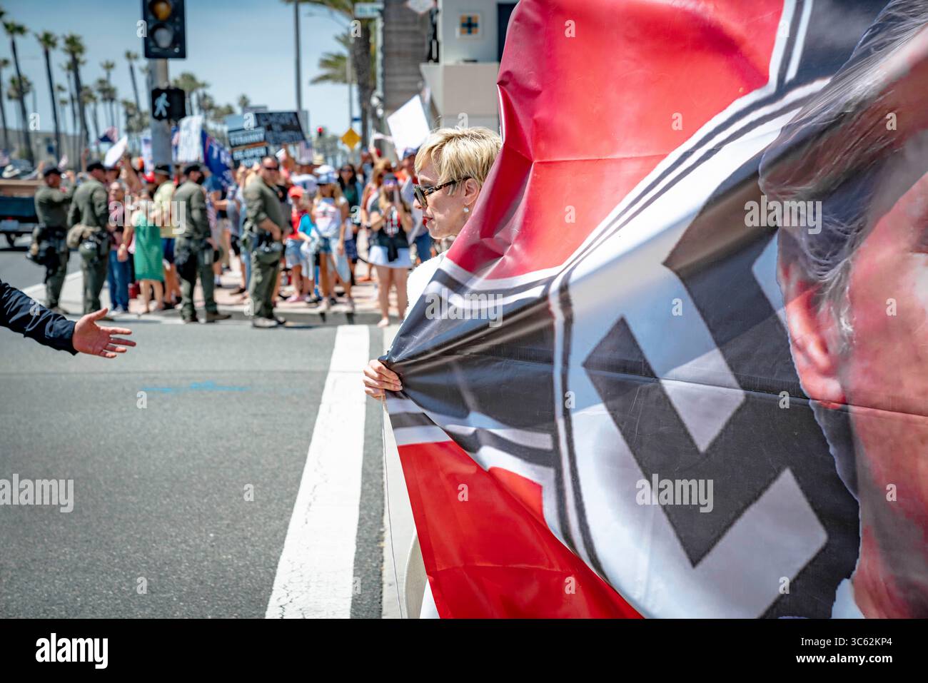 9. Mai 2020, Huntington Beach, Kalifornien, USA: Der rechte Aktivist Leigh Dundas trägt ein großes Banner, das den Gouverneur mit einem bemalten Hitlerbart zeigt. Während eines Reopen California Protests in der Nähe des Huntington Beach Pier. (Kreditbild: © Orin Louis/ZUMA Wire) Stockfoto