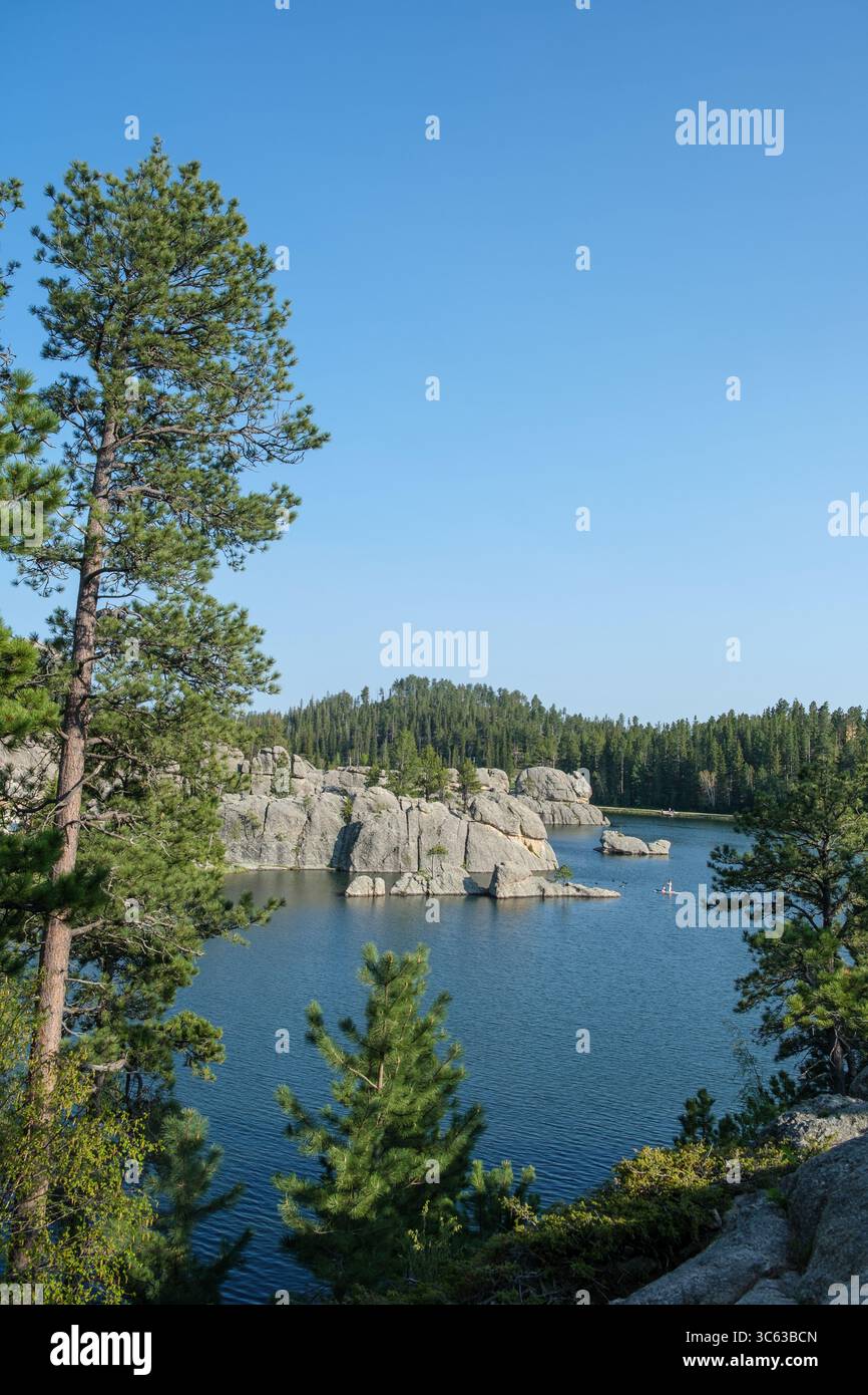 Der Rocky Sylvan Lake in den Black Hills in South Dakota glitzert an einem warmen Sommertag, umgeben von Granitblöcken, Kiefern und ruhigem blauem Wasser. Stockfoto