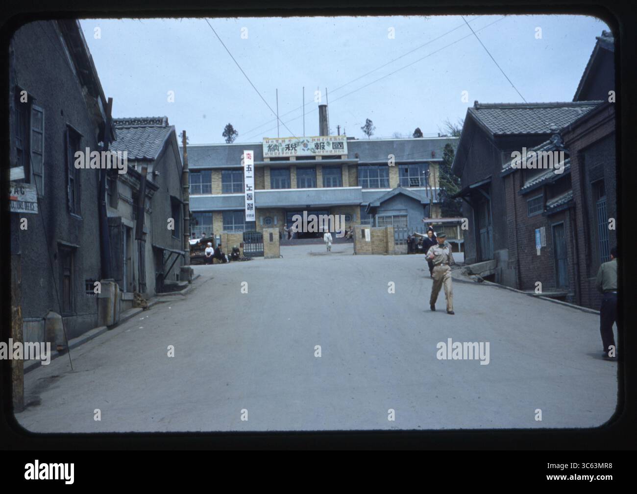 Blick bergauf zum Vordereingang des Inchon Rathauses in Incheon, Südkorea, im Mai 1955. Mehrere Menschen können auf der ruhigen Straße laufen und sitzen, darunter ein Mann in US-Militäruniform. Das Stadtgebäude der Nachkriegszeit weist koreanische Schilder und eine Architektur aus der Mitte des Jahrhunderts auf, die den zivilen Wiederaufbau in den Jahren nach dem Koreakrieg widerspiegelt. Stockfoto