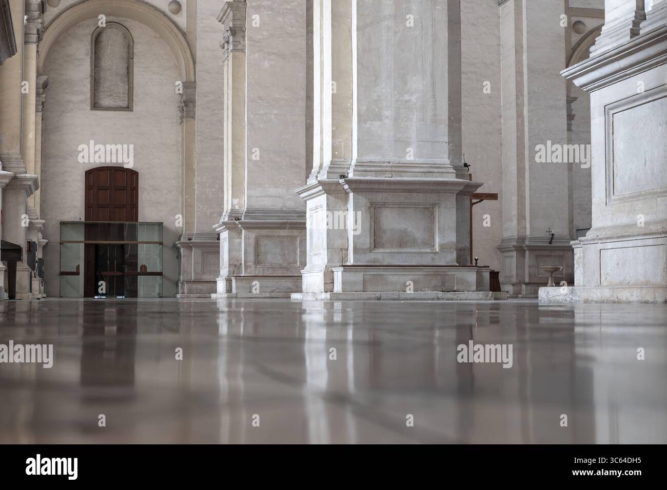 Polierte Steinböden spiegeln die umliegenden Säulen und Bögen wider, die die Pracht der Kathedralarchitektur zeigen. Innenarchitektur der Kathedrale Stockfoto