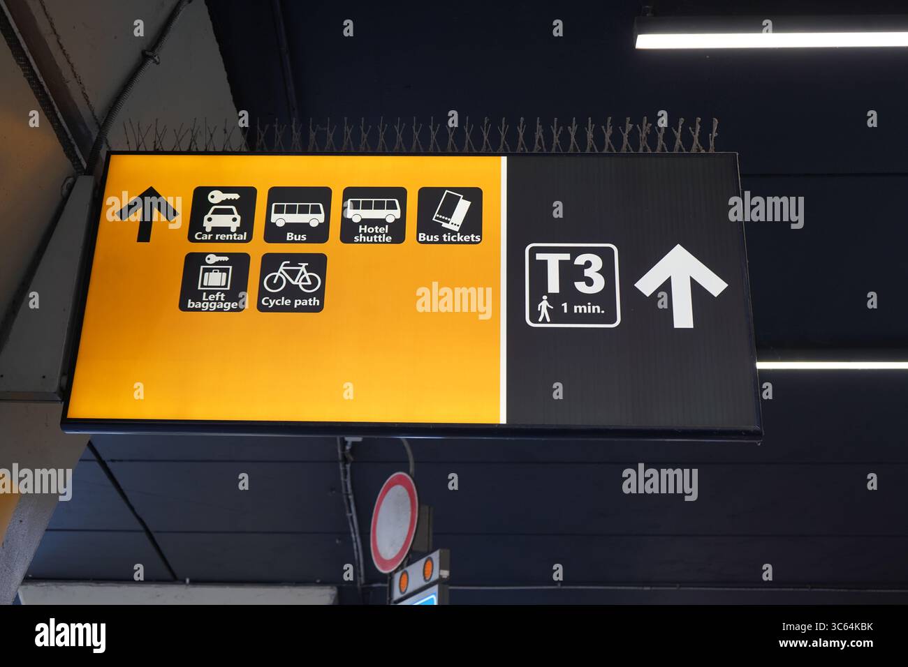 Gelbes Richtungsschild am Flughafen Fiumicino Rom mit Pfeilen für Autovermietung, Bus, Hotel-Shuttle, Ticketausstellung, Gepäckservice und Terminal 3 Gehweg. Stockfoto