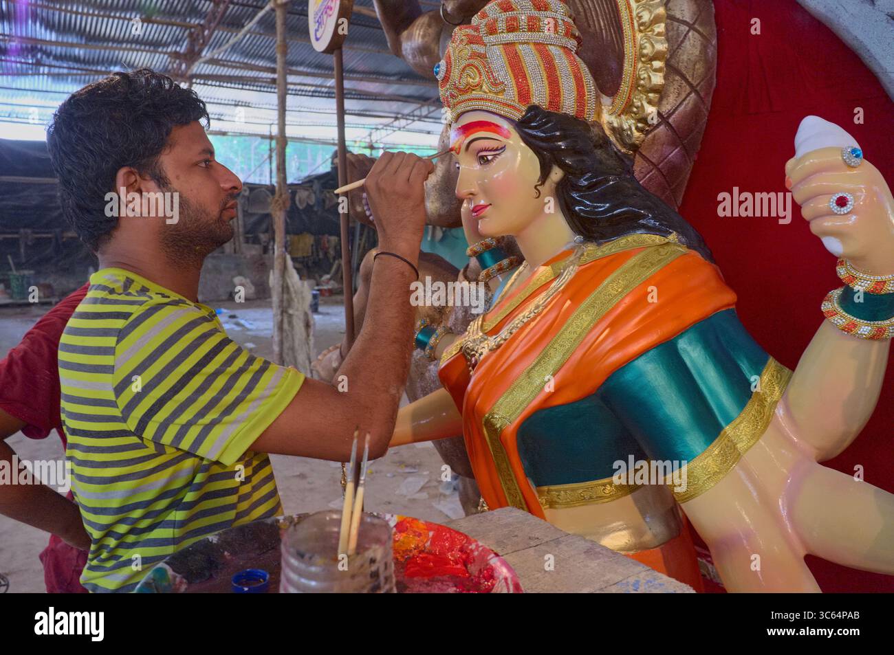 In Vorbereitung auf das Hindu-Festival verleiht Durga Puja, eine Künstlerin in einer Werkstatt in Parel, Mumbai, Indien, einem Göttin den letzten Schliff Stockfoto