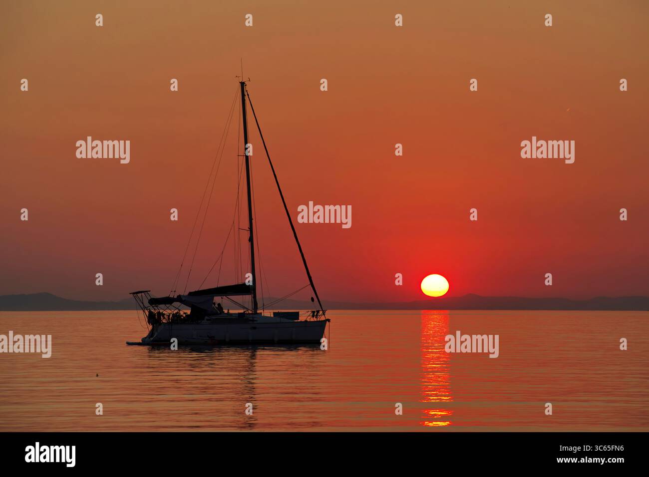 Barca a vela al tramonto sull'acqua calma della baia di Platarià Stockfoto