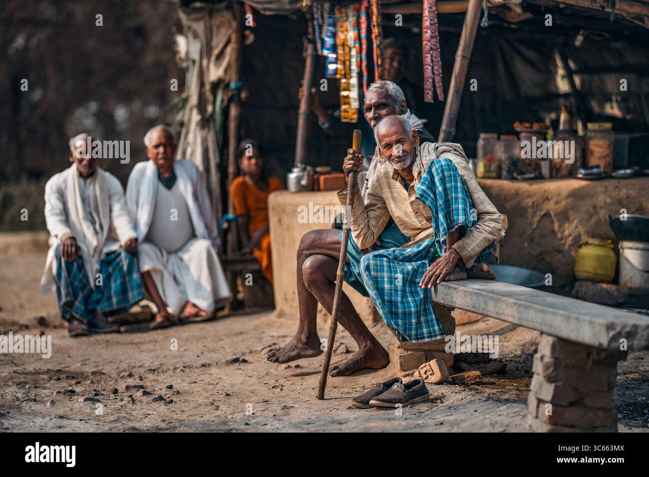 Kalkutta, Indien - 28. Januar 2023: Blick auf verwitterte Gesichter und lebendige Stoffe versammeln sich im warmen Glanz eines bescheidenen Straßenladens, einem Tableau aus ländlichen Li Stockfoto