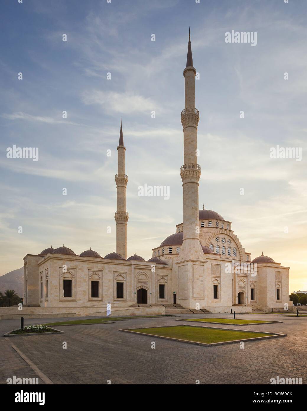 Blick auf die große weiße Moschee, die das sanfte Leuchten der untergehenden Sonne reflektiert, die riesigen Minarette, die den pastellfarbenen Himmel durchdringen, Muscat, Muscat Governorate, Stockfoto