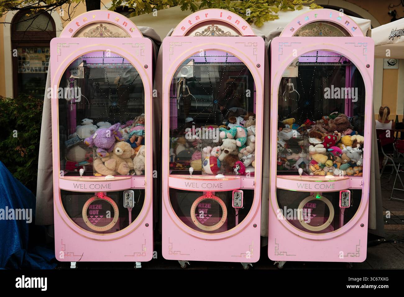Drei rosafarbene Klauenautomaten mit Plüschspielzeug stehen auf der Stadtstraße. Farbenfrohe und verspielte Kontraste in der urbanen Umgebung. Sombor, Serbien - 18. Juli Stockfoto