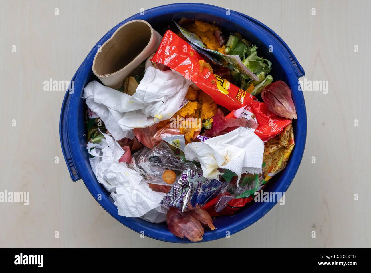 Ein blauer Kunststoffeimer ist mit Hausmüll und Müll gefüllt. Draufsicht. Stockfoto