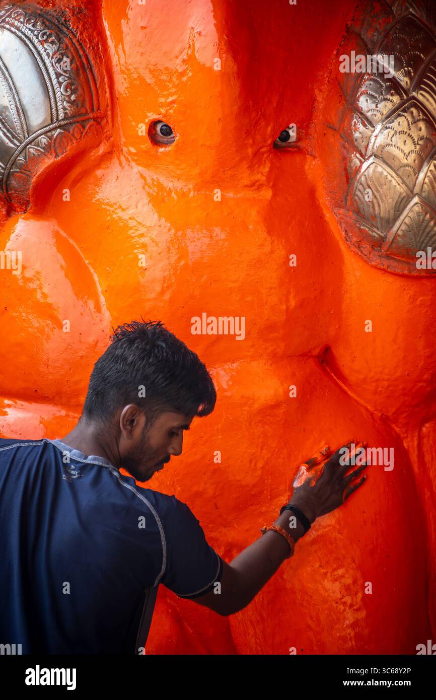 Ein Mann fügt einem Idol in Varanasi, Indien, einen neuen Anstrich hinzu Stockfoto