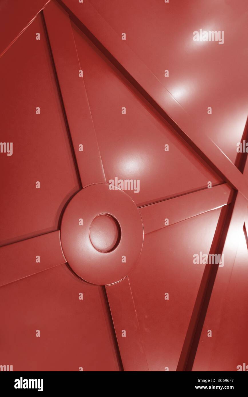 Rote Wandverkleidung mit geometrischem Muster. Vertikales Bild der satinierten Wandplatte, die helle Lichter reflektiert. Stockfoto