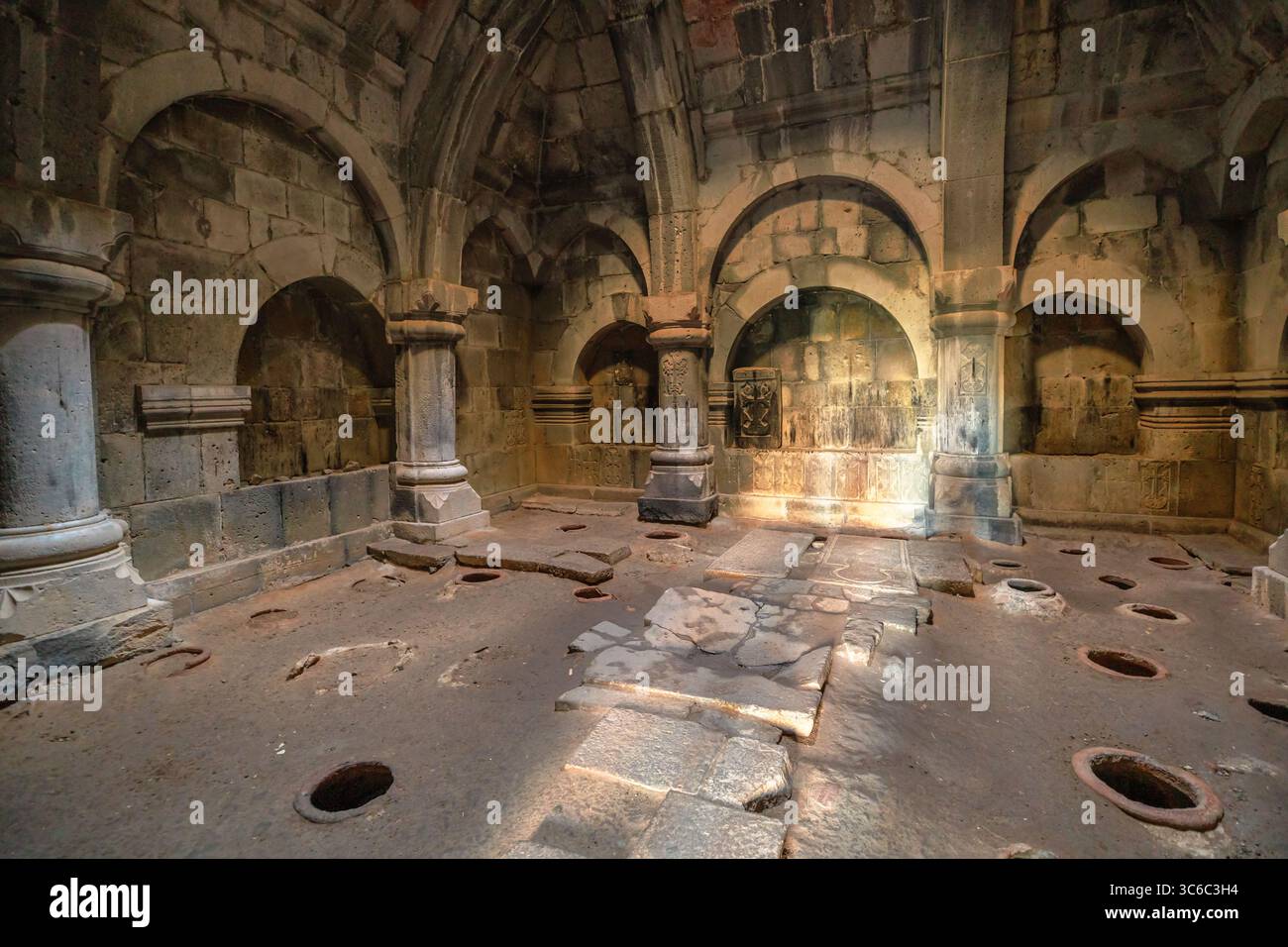 Das Sonnenlicht, das in die antike Bibliothek und das Scriptorium des Klosters Haghpat strömt, beleuchtet den abgenutzten Steinboden, die Säulen und die gebogenen Nischen Stockfoto