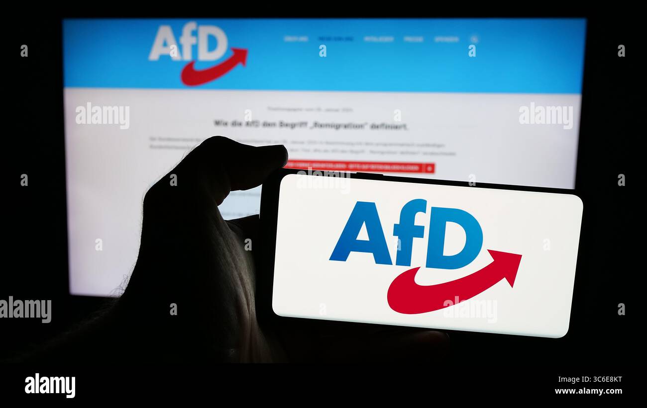Stuttgart, Deutschland - 26.06.2025: Person, die ein Mobiltelefon mit dem Logo der deutschen Alternative Pelz Deutschland (AfD) auf dem Bildschirm vor der Webseite hält. Stockfoto
