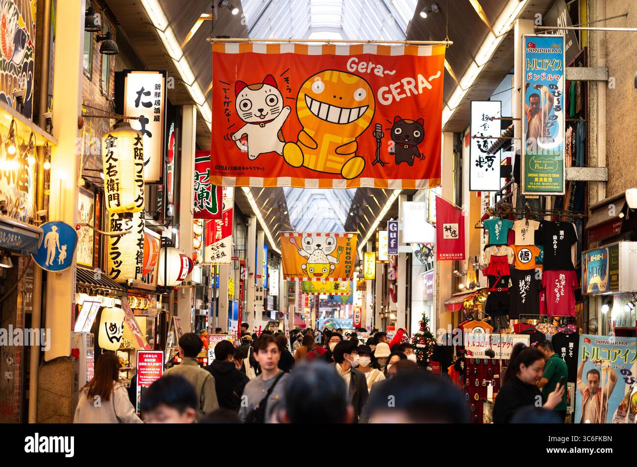 Überfüllte japanische Einkaufsstraße mit farbenfrohen Schildern und Cartoon-Bannern Stockfoto