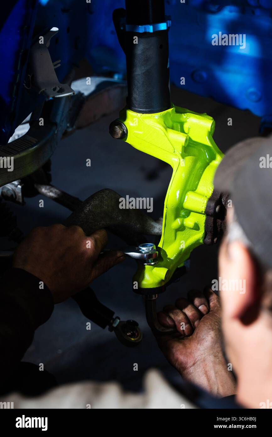 Einbau der Rennscheibenbremse mit leuchtend grünem Achsschenkel an der Aufhängung. Einbau der Vorderradaufhängung und der Bremsscheibe. Einbau der Performance-Federung Stockfoto