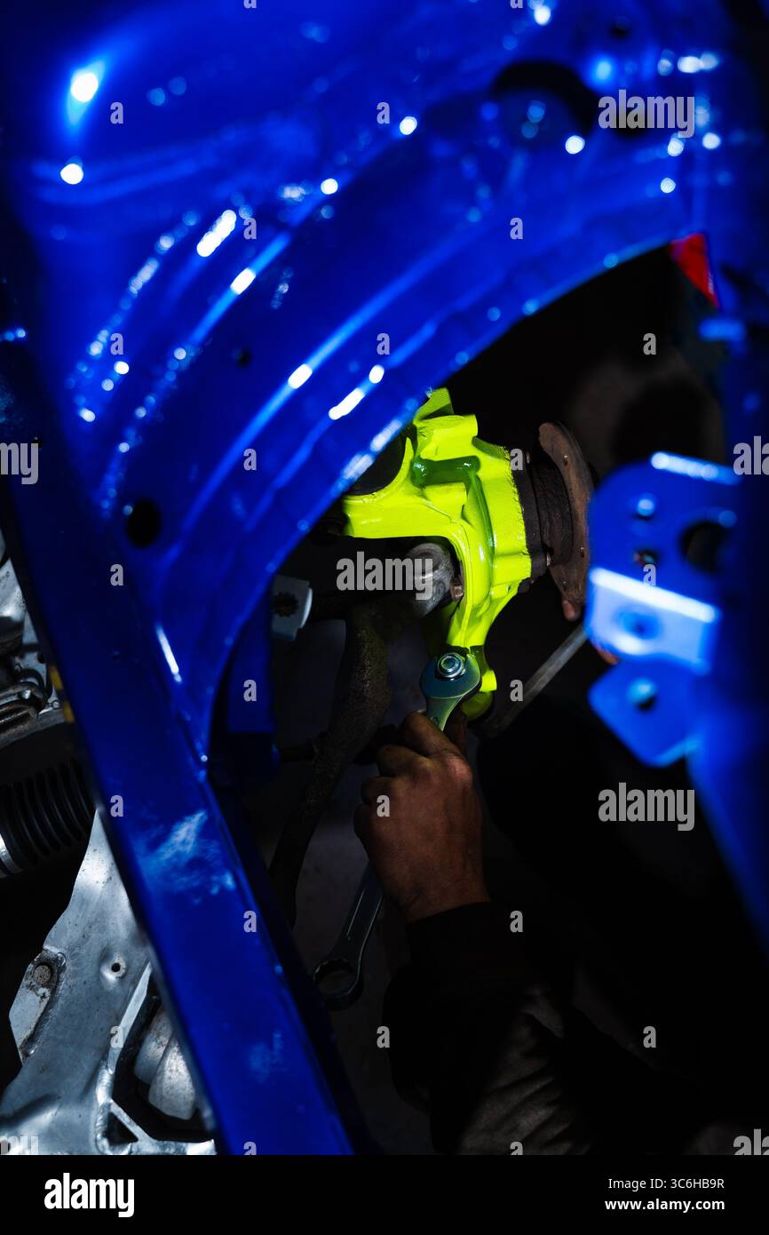 Einbau der Performance-Federung und Bremsscheibe für Drift-Kontrolle und Bremsen. Einbau der Rennscheibenbremse mit leuchtend grünem Achsschenkel an der Aufhängung. Stockfoto