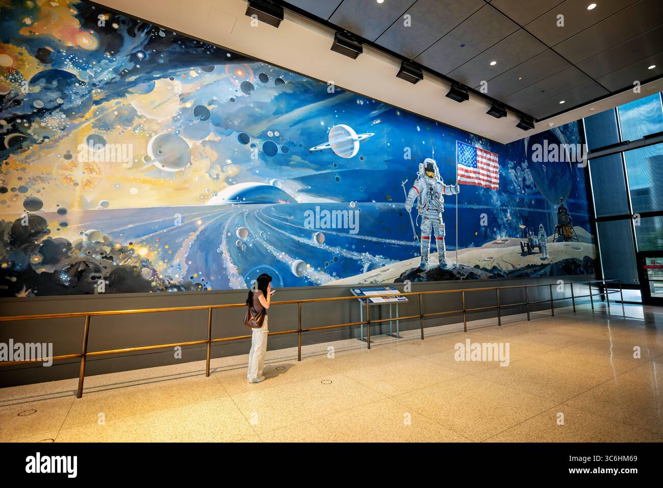 Robert McCalls Wandgemälde "Eine kosmische Ansicht" im National Air and Space Museum in Washington DC | WASHINGTON — Ein Besucher verweilt unter Robert McCalls Wandgemälde "Eine kosmische Ansicht" in der Boeing Milestones of Flight Hall des National Air and Space Museum in Washington, D.C. McCall malte das 58,5-mal-75-Fuß (17,8 mal 22,9 m) große Acrylwerk für die Eröffnung des Museums am 1. Juli 1976 und stellte einen Astronauten dar, der die amerikanische Flagge auf dem Mond pflanzt, vor dem Hintergrund von Planeten und der Milchstraße. Stockfoto