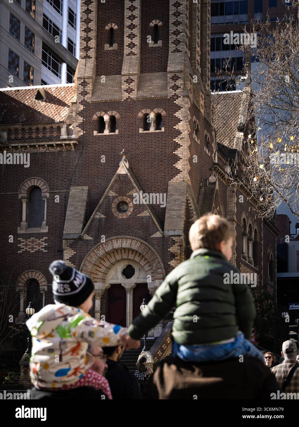 Zwei Kinder, die die Hände an die Schulter der Eltern halten, alte Backsteinkirche Stockfoto