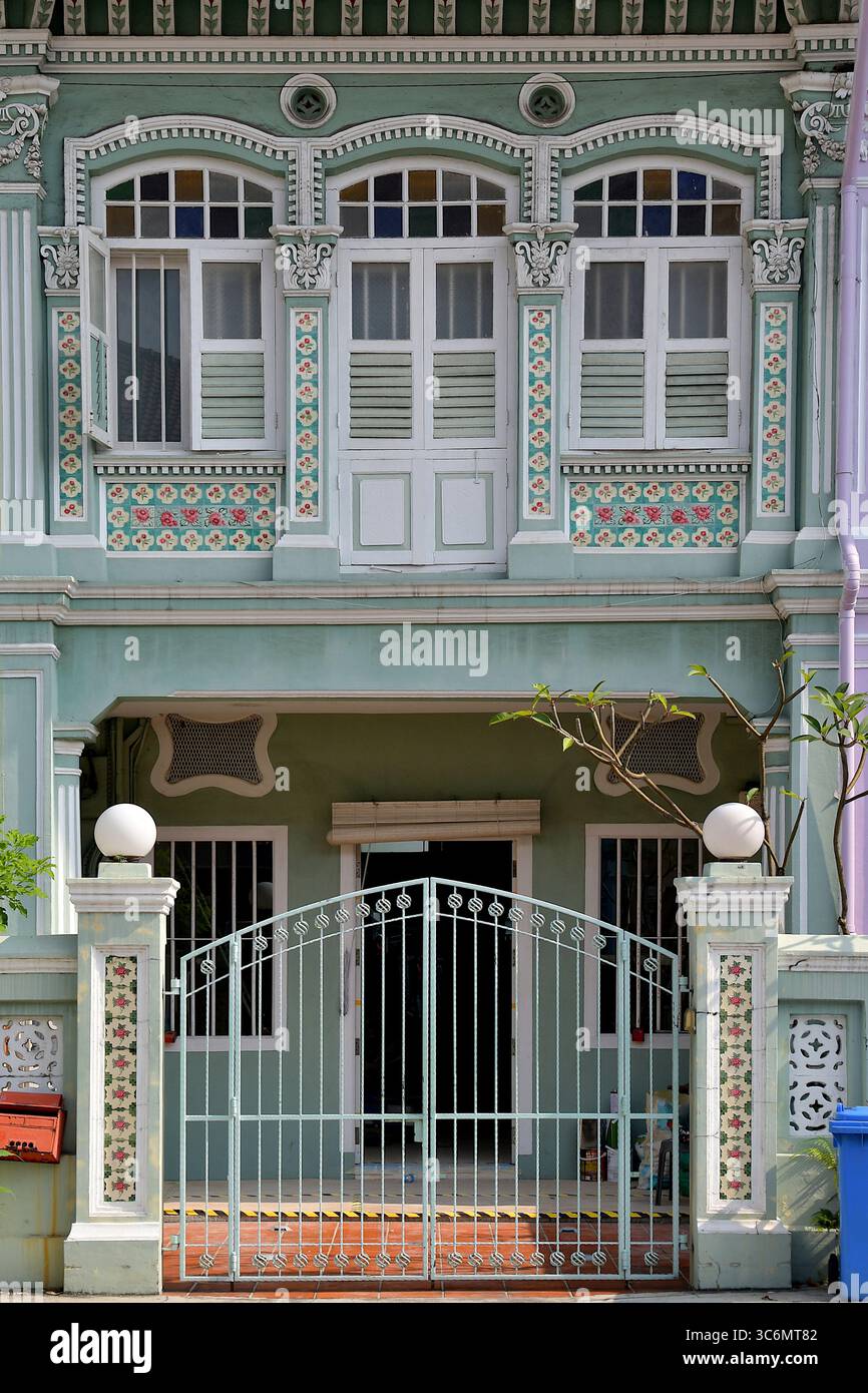 Fassade eines hellgrünen, konservierten Straits Chinese Peranakan Terrassenhauses mit verzierten Rokoko-Putzarbeiten und bunten Mosaikfliesen Stockfoto