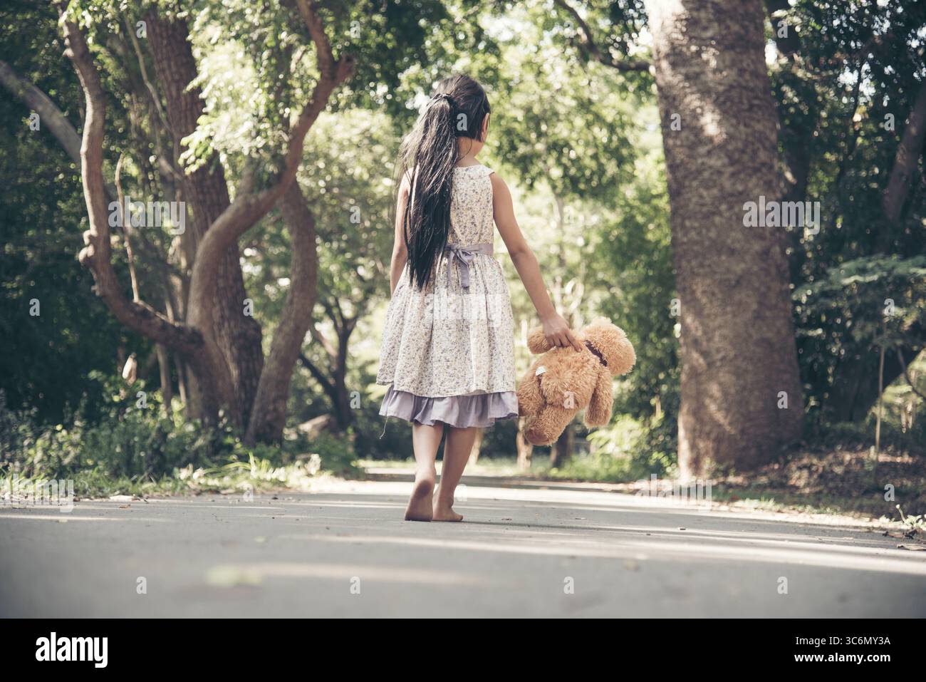 Trauriges Mädchen umarmt Teddybär Traurigkeit allein im grünen Garten Park. Einsames Mädchen Gefühl traurig unglücklich zu Fuß im Freien mit besten Freund Spielzeug. Autismus Kind pl Stockfoto