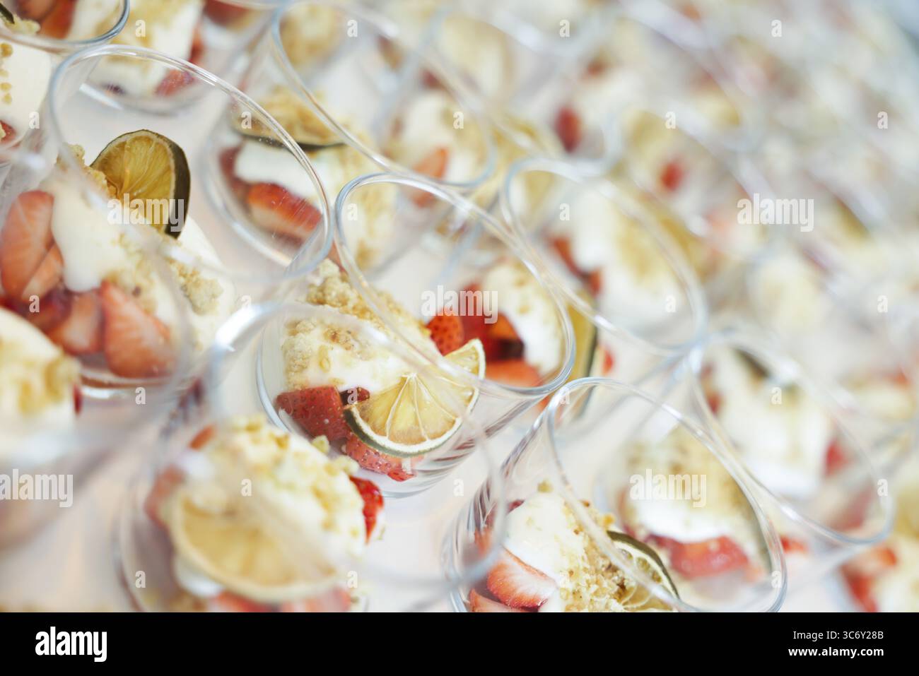 Mehrere Gläser cremiges Dessert und Obst, darunter Erdbeeren und Limettenscheiben am Buffet, Köln, Nordrhein-Westfalen, Deutschland Stockfoto