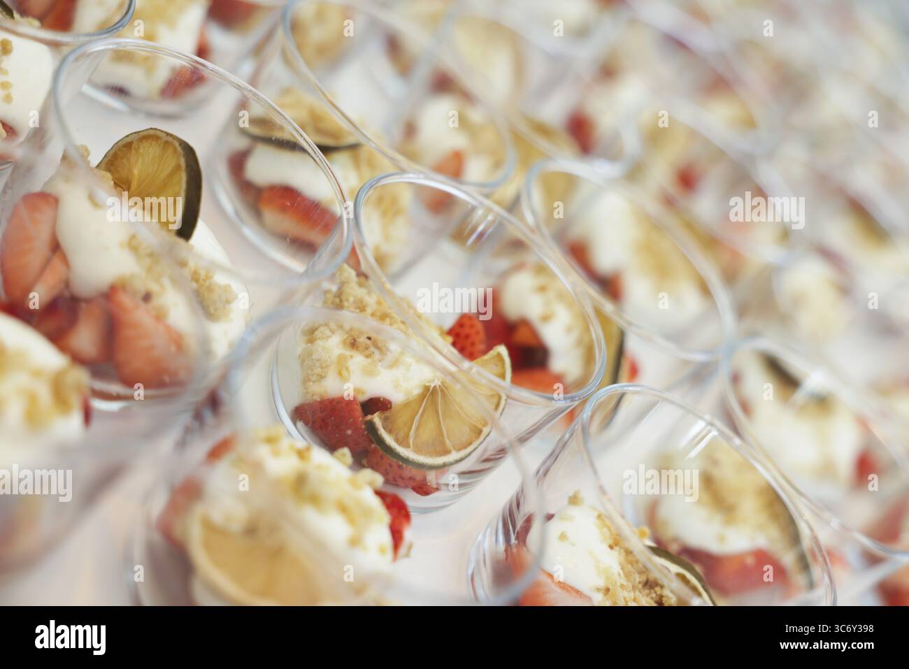 Mehrere Gläser cremiges Dessert und Obst, darunter Erdbeeren und Limettenscheiben am Buffet, Köln, Nordrhein-Westfalen, Deutschland Stockfoto