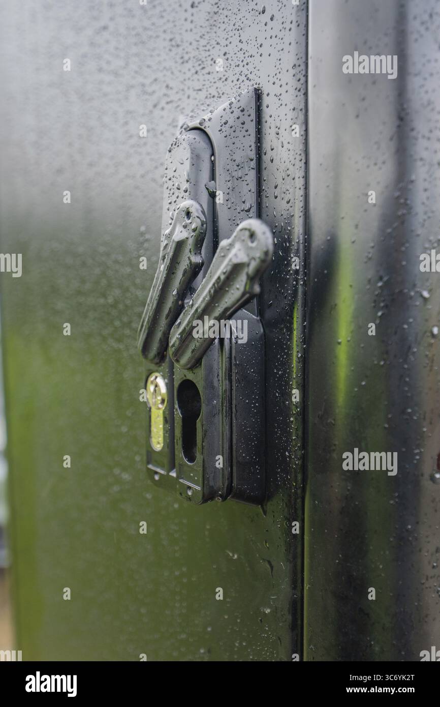 Nassschloss an einer schwarzen Tür mit sichtbaren Wassertropfen und reflektiertem Licht, Installation einer Ladestation für Elektroautos, Calw, Deutschland Stockfoto