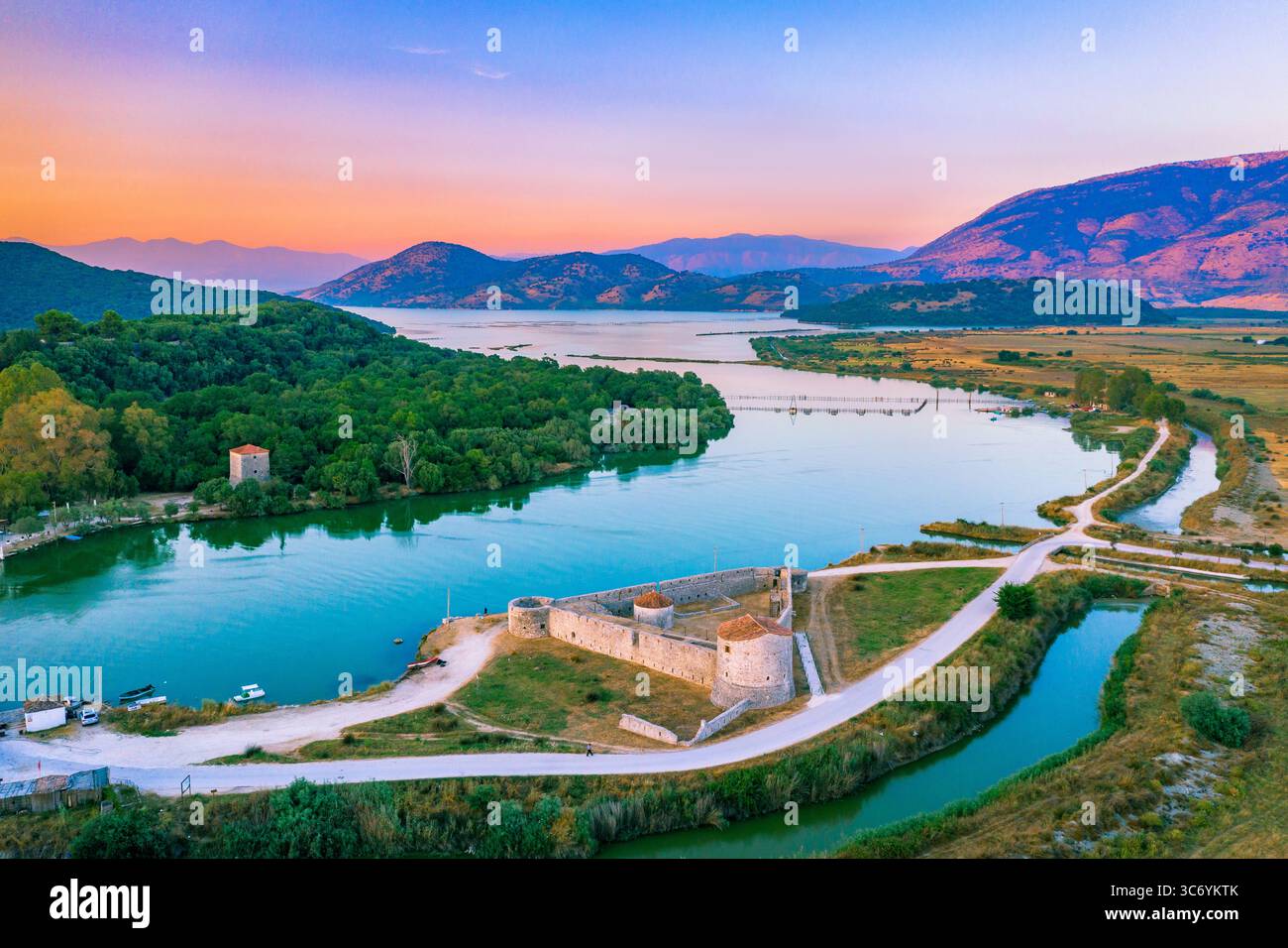 Butrint Nationalpark mit venezianischer Burg, Lagune und Bufi Fluss mit Fährüberfahrt, Butrint, Albanien bei Sonnenuntergang. Stockfoto