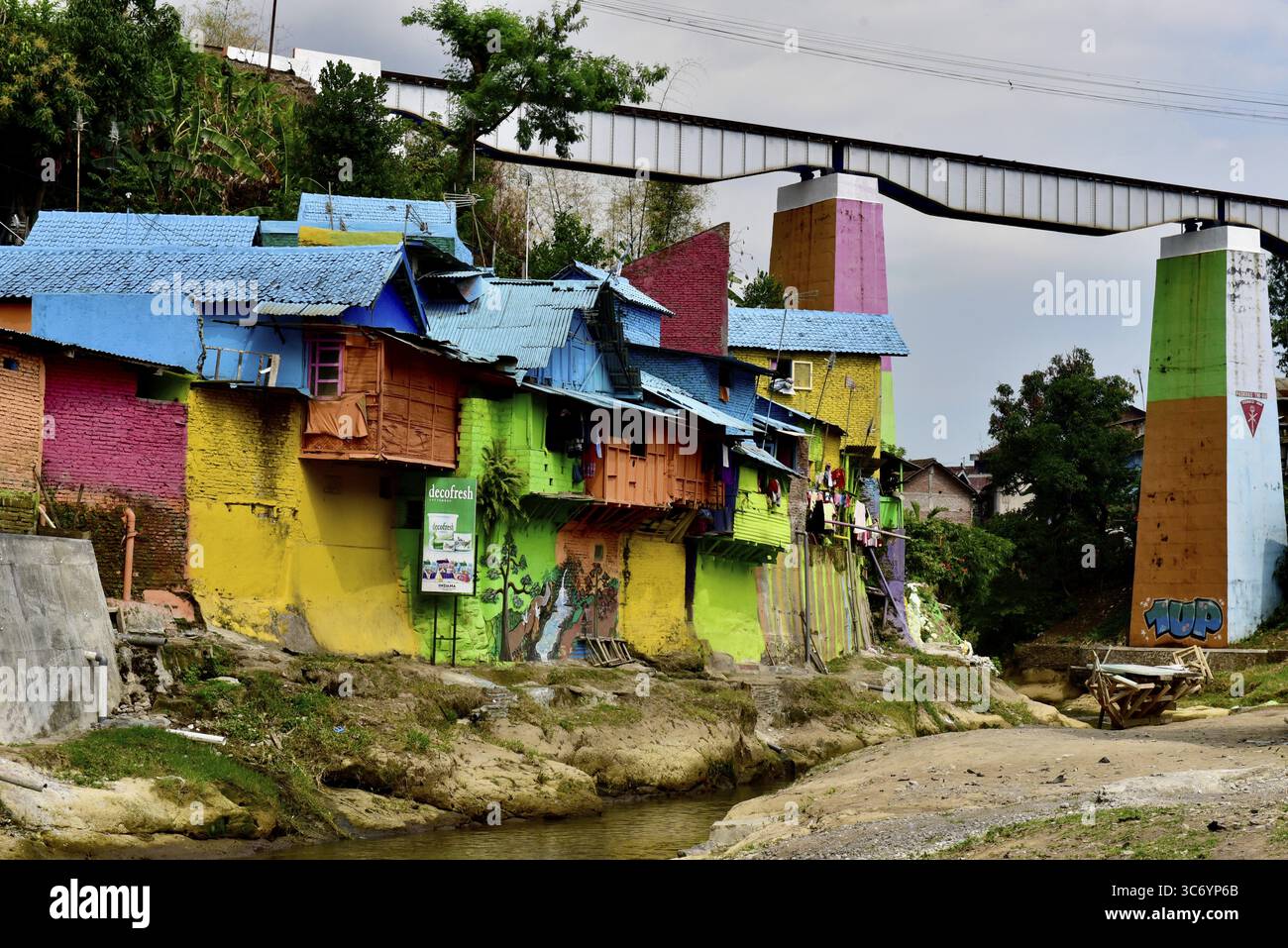 Farbenfrohes Viertel mit blauen und gelben Gebäuden und einer Brücke im Hintergrund, Kampung Warna, Malang, Batu, Java, Indonesien Stockfoto