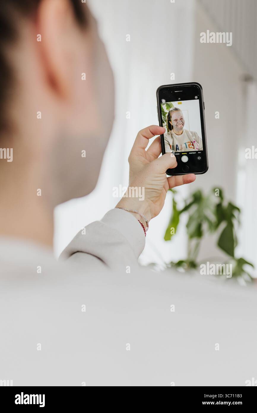 Frau lächelt und nimmt Selbstporträts mit der Telefonkamera im Selfie-Modus auf Stockfoto