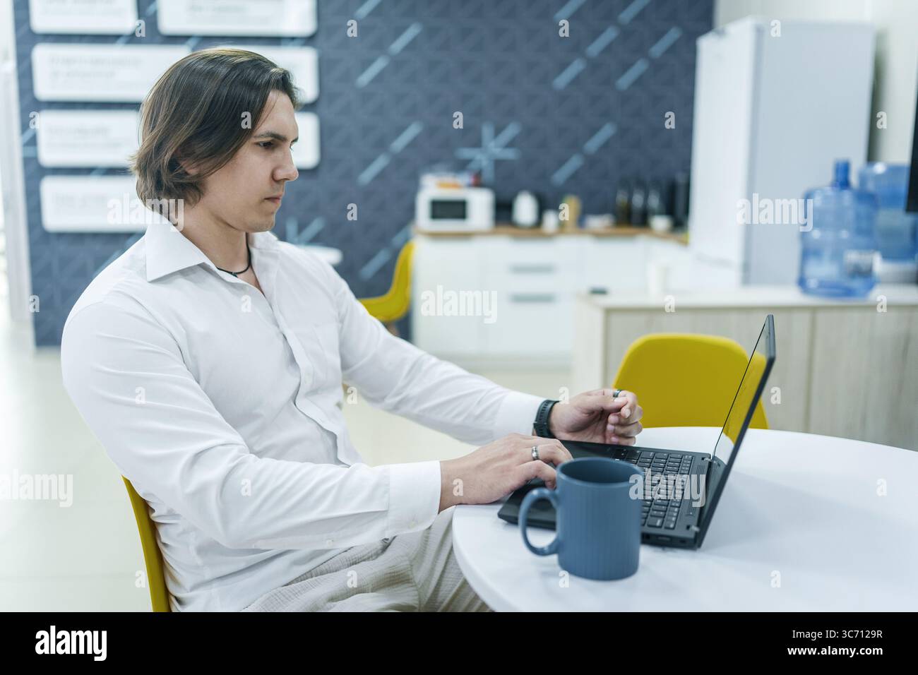 Mann, der im Büro mit Kaffee am Laptop arbeitet. Fokussierter Look. Stockfoto