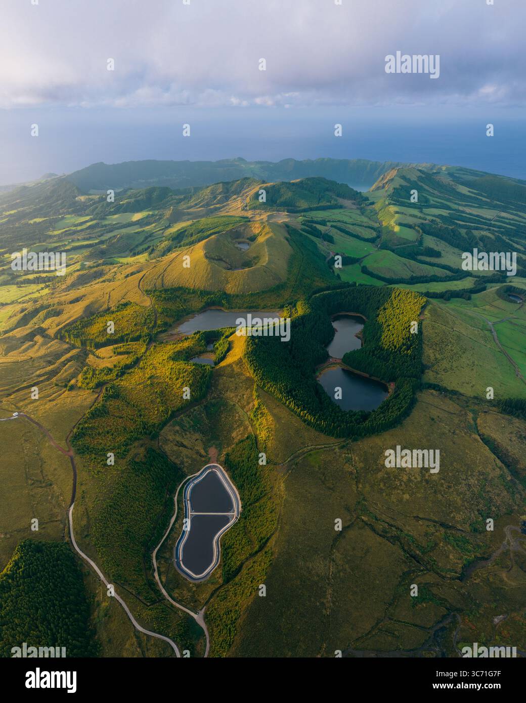 Blick aus der Vogelperspektive auf Zwillingsseen, eingebettet in grüne Hügel, ein Wandteppich aus Licht und Schatten, der die Landschaft in Kontrasttönen malte, Sete Cidades, Portugal. Stockfoto